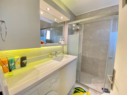 La salle de bains est pourvue d'un lavabo et d'une douche en verre. dans l'établissement Impressive flat in the heart of Alsancak, à Konak