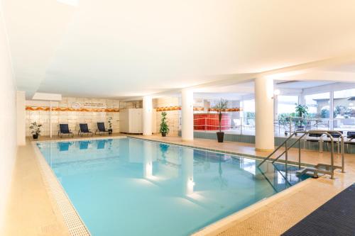 a large indoor swimming pool with blue water at Bodensee Loft - 116 m² Traumwohnung in Uhldingen-Mühlhofen