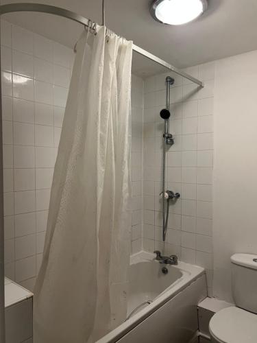 a bathroom with a bath tub with a shower curtain at Luxury Studio Apartment in Manchester
