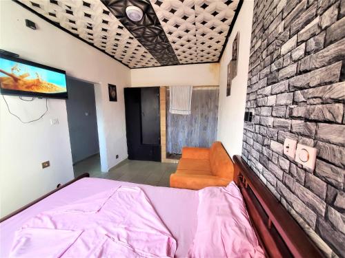a bedroom with a bed and a tv on a brick wall at The Yafé Bastos 7 in Yaoundé