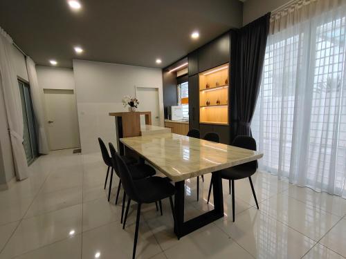 Cozy House in Kajang في كاجانغ: غرفة طعام مع طاولة وكراسي سوداء