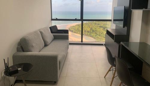a living room with a couch and a large window at BARRA FLATS BY LOUI in Recife