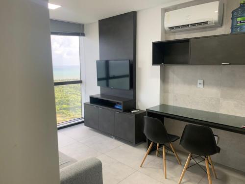 a kitchen with two chairs and a counter with a tv at BARRA FLATS BY LOUI in Recife