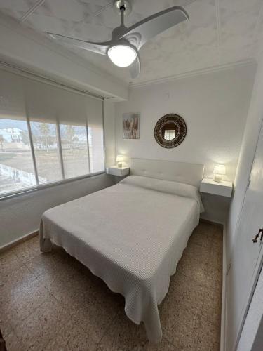 ein weißes Schlafzimmer mit einem Bett und zwei Fenstern in der Unterkunft Almenara Beach in Almenara