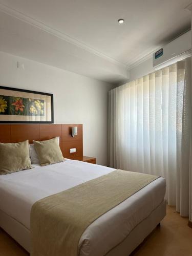 a bedroom with a large bed and a window at Europeia Hotel in Caldas da Rainha