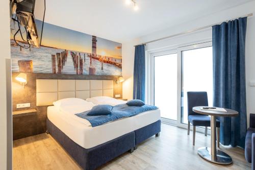 ein Schlafzimmer mit einem Bett und einem Tisch und einem Fenster in der Unterkunft Familien- und Aparthotel Strandhof in Tossens
