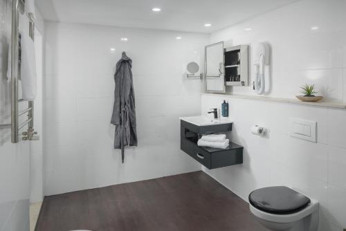 a white bathroom with a toilet and a sink at Hotel Tomi in Portorož