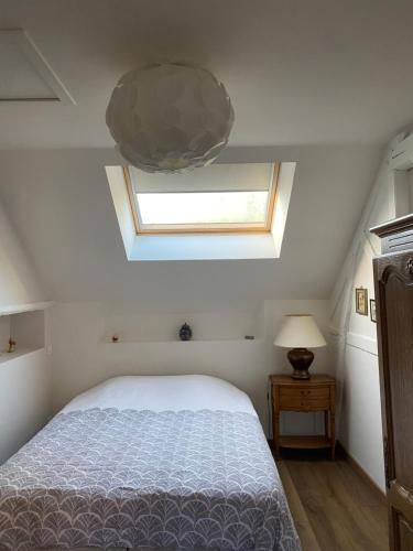 ein Schlafzimmer mit einem Bett und einem Dachfenster in der Unterkunft Maison familiale au coeur de la vallée de l'Eure in Breuilpont