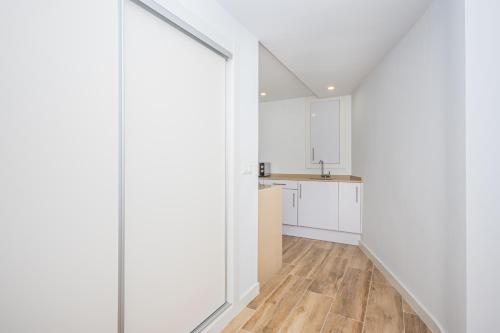 a kitchen with white walls and wooden floors at Vila Playa in Villajoyosa