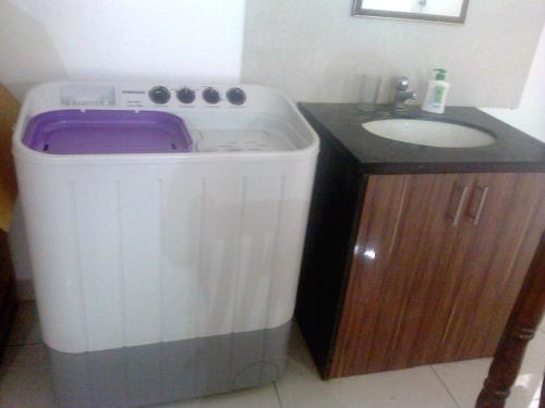 a bathroom with a washing machine next to a sink at WeKare Archid Royal Service Apartment in Bhubaneshwar
