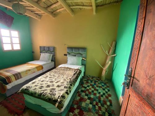 two beds in a room with green walls at riad jnane imnane in Tamguist