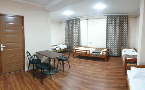 Habitación con cama, mesa y sillas. en Bee happy Hostel, en Dalandzadgad