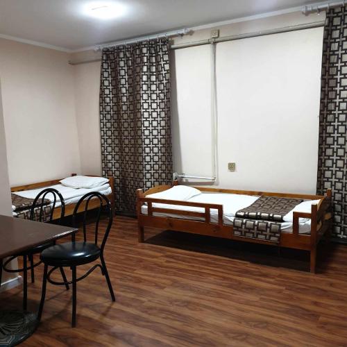 a room with two beds and a table and chairs at Bee happy Hostel in Dalandzadgad