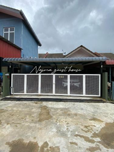a building with a fence with a sign on it at Najma guest house in Kota Bharu
