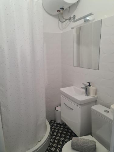 a white bathroom with a toilet and a sink at Apartman Zlatovo Stan Na Dan in Požarevac