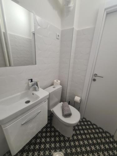 a white bathroom with a toilet and a sink at Apartman Zlatovo Stan Na Dan in Požarevac