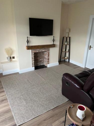 a living room with a couch and a fireplace at Milltown Cottage in Aghanloo