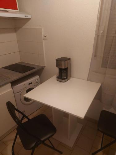- une cafetière assise sur une table blanche dans la cuisine dans l'établissement T2 Montpellier plein sud clim wifi terrasse de 16m2, à Montpellier