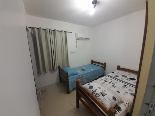 um pequeno quarto com 2 camas e uma janela em Dúplex mar de Pajuçara em Maceió
