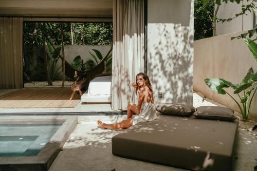 a woman sitting on a bed next to a pool at TOHO VILLA 4BED WITH POOL & JACUZZI in Tulum