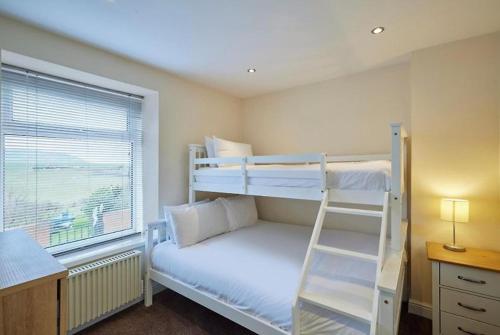 a bedroom with two bunk beds and a ladder at Kurnell Cottage, Staithes in Staithes