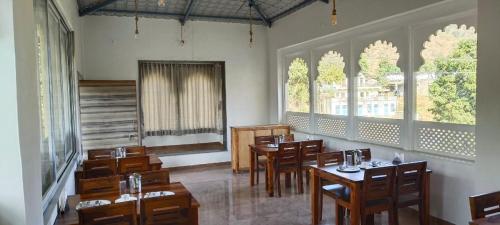 un restaurante con mesas y sillas de madera y ventanas en Bagmarg Haveli Kumbhalgarh, en Rājsamand