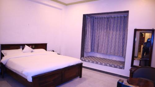 een slaapkamer met een bed, een spiegel en een raam bij Bagmarg Haveli Kumbhalgarh in Rājsamand