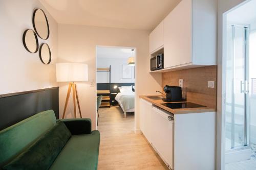 un salon avec un canapé vert et une cuisine dans l'établissement Royale - Hypercentre, à Orléans