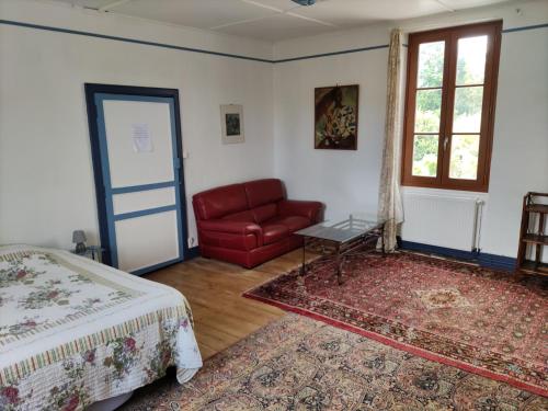 um quarto com uma cama e um sofá vermelho em le jardin du controleur em Valence-dʼAgen