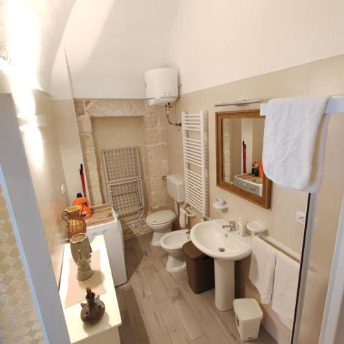 a bathroom with a sink and a toilet and a mirror at Home Pugliese in Ceglie Messapica