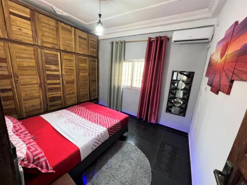 a bedroom with a red and white bed and a window at The Yafé Bastos 13 in Yaoundé