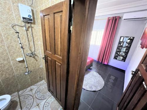 een badkamer met een douche en een houten deur bij The Yafé Bastos 13 in Yaoundé