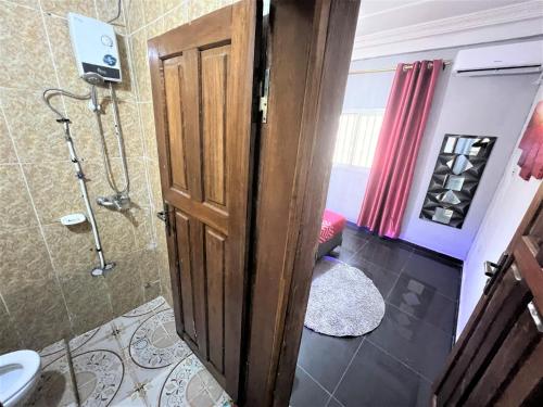 a bathroom with a shower and a wooden door at The Yafé Bastos 13 in Yaoundé