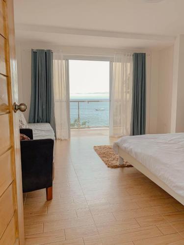 a bedroom with a bed and a view of the ocean at CasaDel Beach House in Mabini