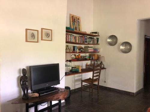 sala de estar con TV y mesa con escritorio en Karamaluu Garden Lodge, en Gunjur