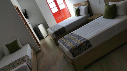 Habitación pequeña con 2 camas y ventana en ALTO VERDE HOTEL, en Guatapé
