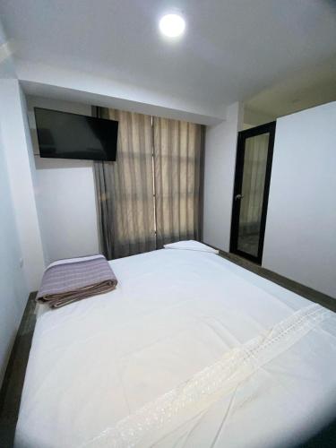 1 cama blanca grande en una habitación con TV en Hostal Huella, en Lambayeque