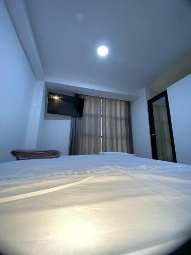 Un dormitorio con una gran cama blanca y una ventana en Hostal Huella, en Lambayeque
