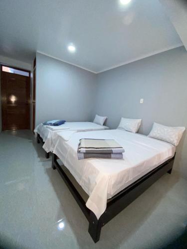 Una cama grande con sábanas blancas y toallas. en Hostal Huella, en Lambayeque
