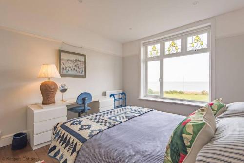 a bedroom with a bed with a desk and a window at Bayside House in Westgate-on-Sea