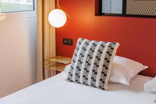 a bedroom with a white bed with a pillow on it at CMG Résidence Canal Saint-Martin Vellefaux in Paris