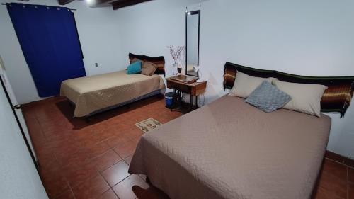 1 dormitorio con 2 camas, mesa y espejo en Hotel Posada Don Papagon en Antigua Guatemala