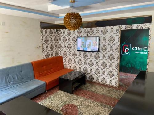sala de estar con sofá y TV en la pared en ClinClia Hotel2, en Ibadán