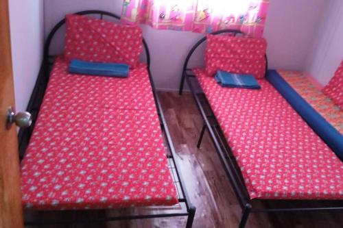 two red beds sitting next to each other in a room at Grace Homestay Kepayan in Kota Kinabalu