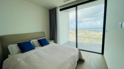 una camera da letto con un letto con cuscini blu e una grande finestra di Mercury Tower Suites a Paceville
