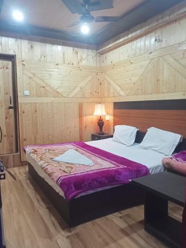 um quarto com uma cama grande e um cobertor roxo em Aapka Ghar Guest House em Bhimtal