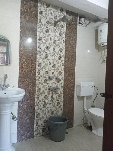 een badkamer met een wastafel, een toilet en een muur bij Aapka Ghar Guest House in Bhīm Tāl