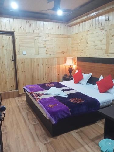 een slaapkamer met een groot bed met paarse en rode kussens bij Aapka Ghar Guest House in Bhīm Tāl