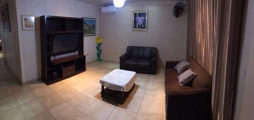 - un salon avec un canapé, une chaise et une télévision dans l'établissement Acogedora Casa Céntrica, à Ciudad del Este
