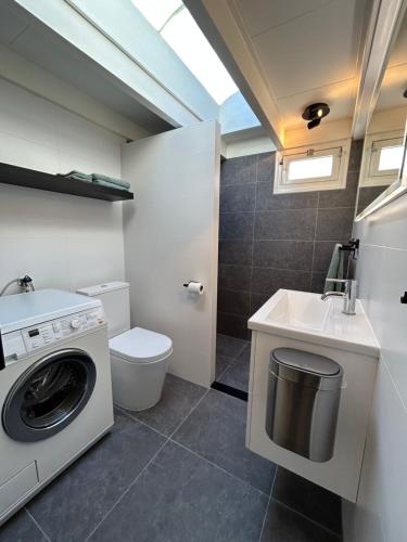 ein Badezimmer mit einer Waschmaschine und einem Waschbecken in der Unterkunft Zandrijk in Egmond aan den Hoef